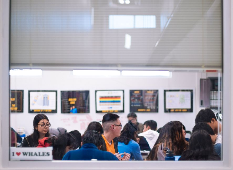 High school students actively learning in a well-lit classroom setting with educational posters.