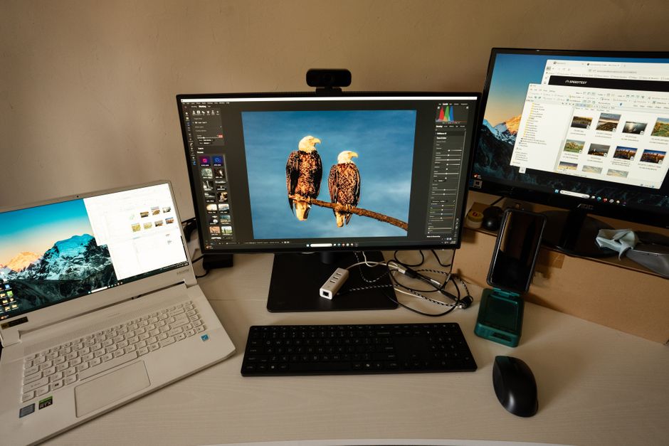 Photographer's workspace with dual monitors, laptop, and editing software.